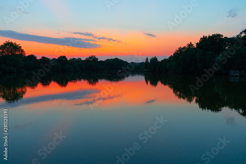 tranquil  twilight sunset shot over lake with reflections of sky and clouds in water and rowing boats to centre of lake