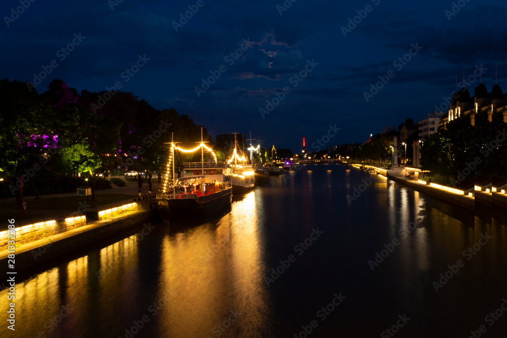 Night view of illuminated restaurant ships with reflection in the water of the river Auraioki, the night landscape of Turku with illumination, the life of the night city. City of Turku, Finland.