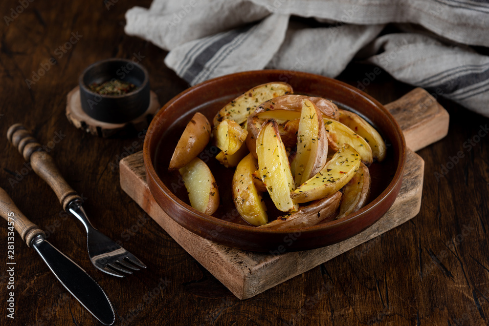 Baked potato in a plate on a wooden background, top view