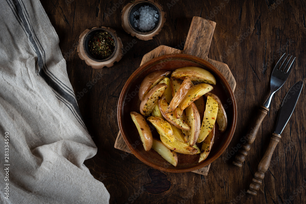 Baked potato in a plate on a wooden background, top view