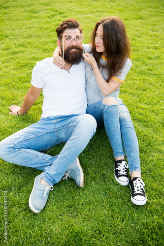 Perfect pair for perfect couple. Couple in love having fun with prop glasses. Couple of bearded man and sexy woman on green grass. Family couple relaxing on summer day
