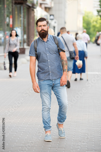 Guy exploring city. Comfortable tourism. Summer vacation. Sightseeing concept. Backpack for urban travelling. Hipster wearing backpack urban street background. Bearded man travel with backpack © be free