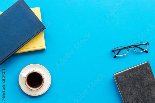 Billede på lærred Books on library desk for reading, coffee, glasses on blue background top view m