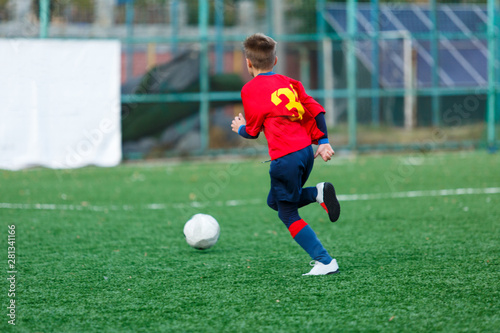 Boys in white and blue sportswear plays  football on field, dribbles ball. Young soccer players with ball on green grass. Training, football, active lifestyle for kids concept  © Natali