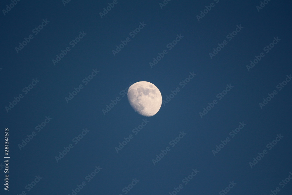 Clear picture of Moon at late sunset taken from family house backyard on dark blue sky background Clear picture of Moon at late sunset taken from family house backyard on dark blue sky background
