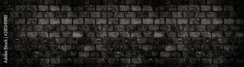 Old and weathered grungy black dark concrete block brick wall texture background abandoned house with holes and cracks and vignetting as scary large panorama wide banner background.