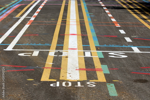 Colorful street line testing site with multiple lines in various colors and shapes with letters painted on paved surface on warm sunny spring day