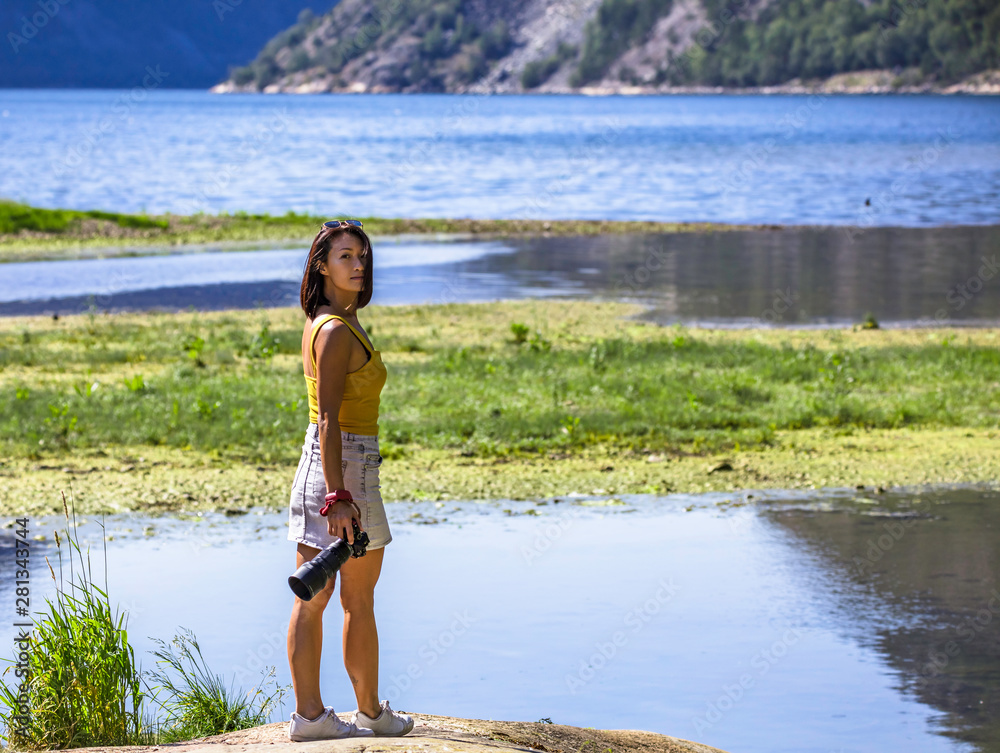 female photographer enjoying the scenic view of Norwegian fjord in the summer