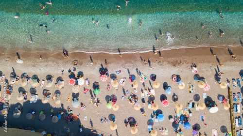 Aerial top view of the sandy beach and blue color sea with sunshade on the sandy beach