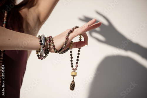 The elegant hand of a woman holding a mala yoga prayer bead necklace and shadow of hand on the background.  photo
