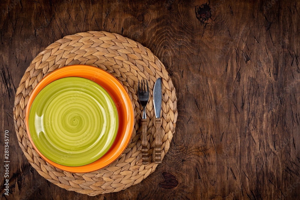 Empty plate with fork and knife on colored wooden background, top view, copy space, mock-up