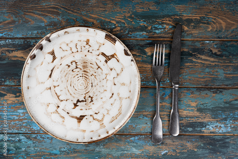 Empty plate with fork and knife on colored wooden background, top view, copy space, mock-up