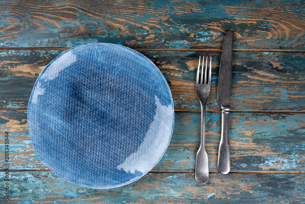 Empty plate with fork and knife on colored wooden background, top view, copy space, mock-up
