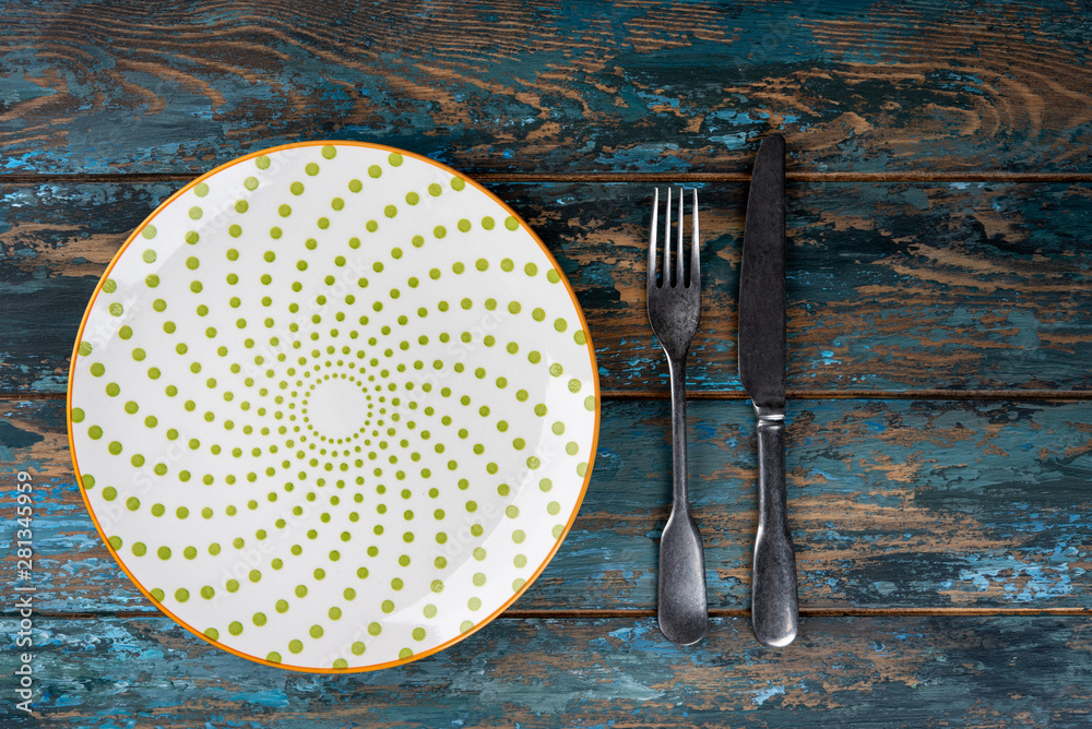 Empty plate with fork and knife on colored wooden background, top view, copy space, mock-up