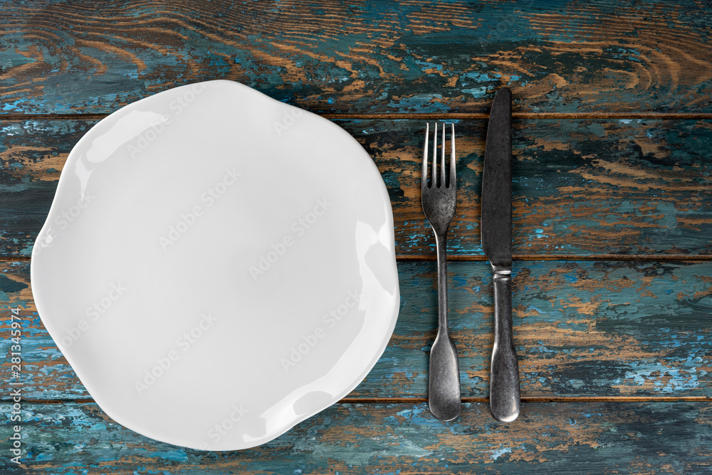 Empty plate with fork and knife on colored wooden background, top view, copy space, mock-up
