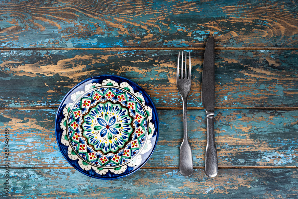 Empty plate with fork and knife on colored wooden background, top view, copy space, mock-up