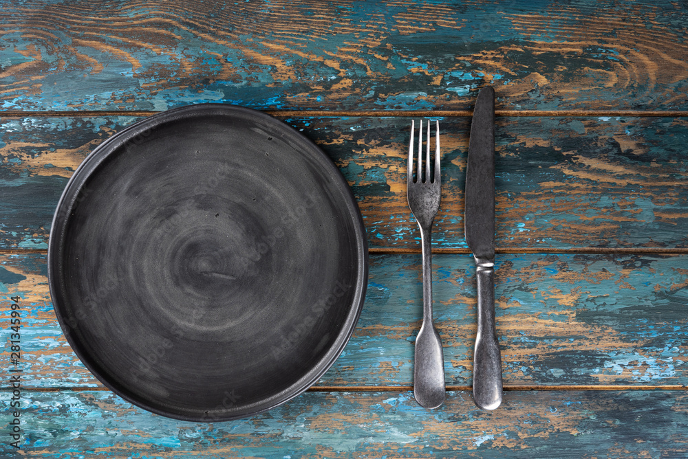 Empty plate with fork and knife on colored wooden background, top view, copy space, mock-up