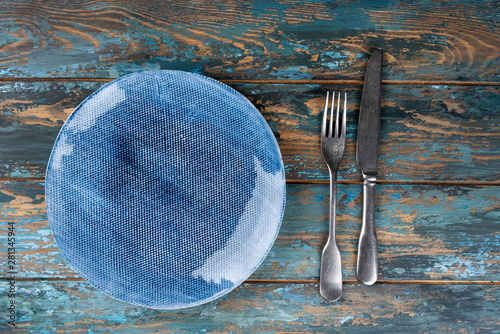 Obraz na płótnie Empty plate with fork and knife on colored wooden background, top view, copy space, mock-up w salonie