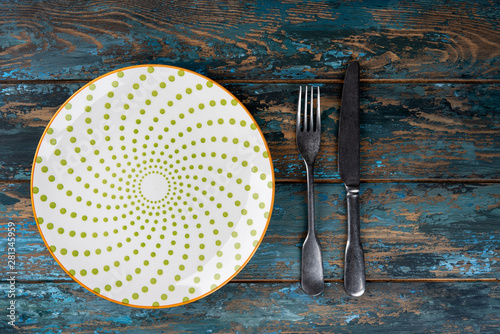Obraz na płótnie Empty plate with fork and knife on colored wooden background, top view, copy space, mock-up w salonie