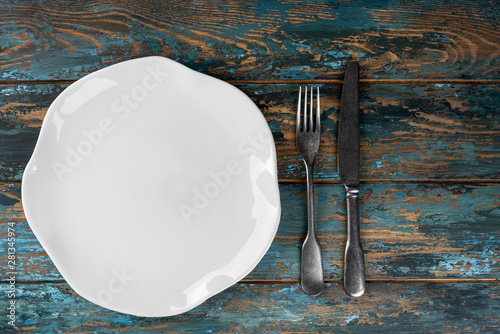 Obraz na płótnie Empty plate with fork and knife on colored wooden background, top view, copy space, mock-up w salonie