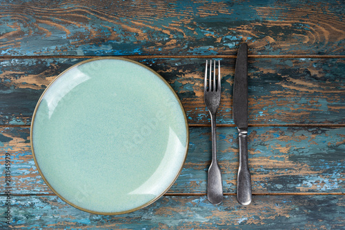 Obraz na płótnie Empty plate with fork and knife on colored wooden background, top view, copy space, mock-up w salonie