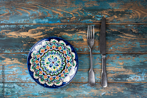 Obraz na płótnie Empty plate with fork and knife on colored wooden background, top view, copy space, mock-up w salonie