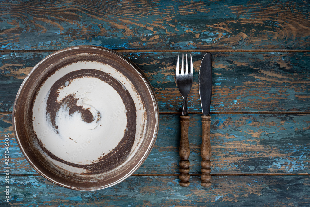 Empty plate with fork and knife on colored wooden background, top view, copy space, mock-up