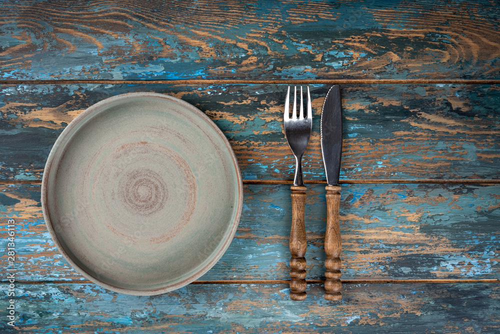 Empty plate with fork and knife on colored wooden background, top view, copy space, mock-up