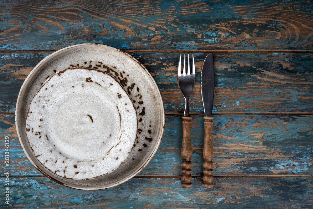 Empty plate with fork and knife on colored wooden background, top view, copy space, mock-up