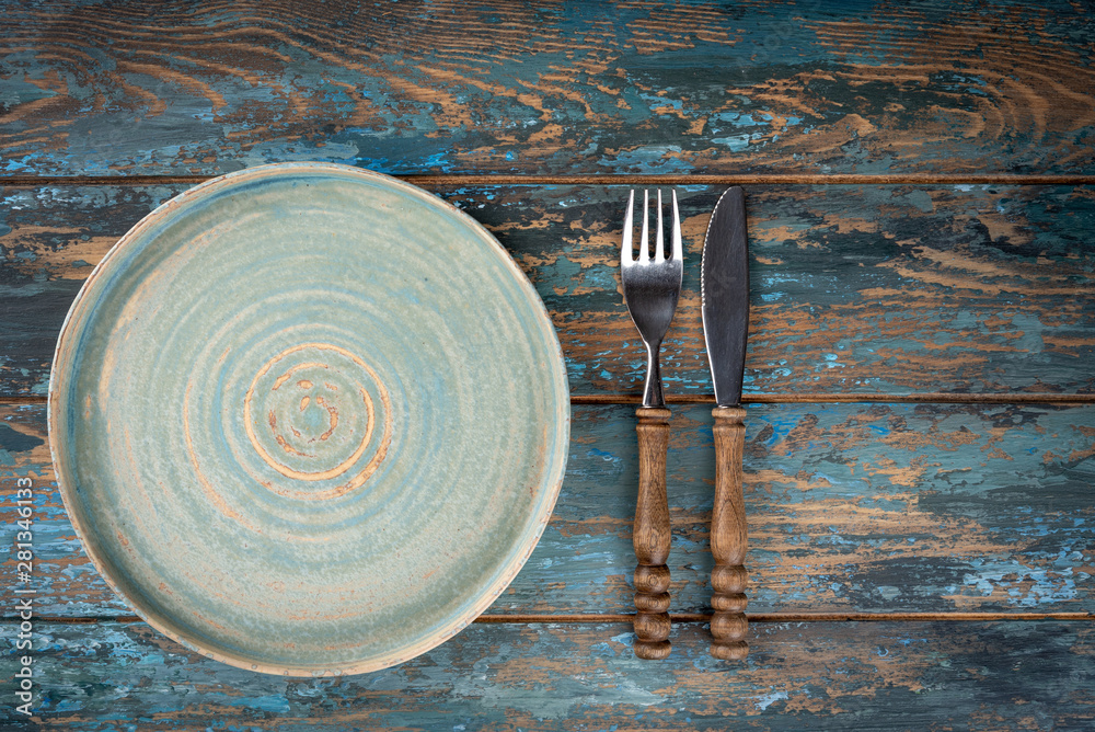 Empty plate with fork and knife on colored wooden background, top view, copy space, mock-up