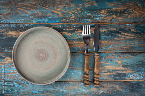 Obraz na płótnie Empty plate with fork and knife on colored wooden background, top view, copy space, mock-up w salonie