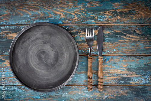 Obraz na płótnie Empty plate with fork and knife on colored wooden background, top view, copy space, mock-up w salonie