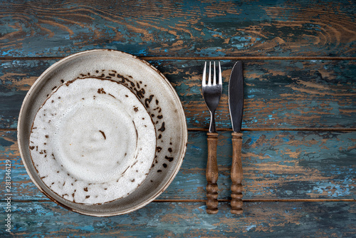 Obraz na płótnie Empty plate with fork and knife on colored wooden background, top view, copy space, mock-up w salonie