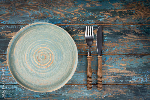 Obraz na płótnie Empty plate with fork and knife on colored wooden background, top view, copy space, mock-up w salonie