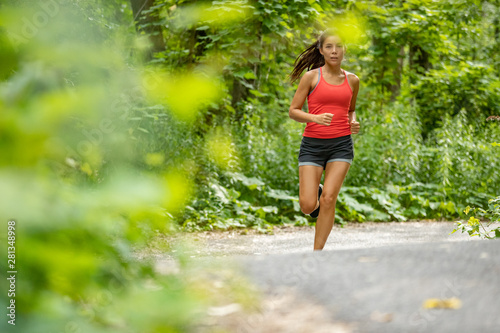 Asian fit girl jogging in park. Young woman running on forest path nature outdoor exercise training cardio workout.