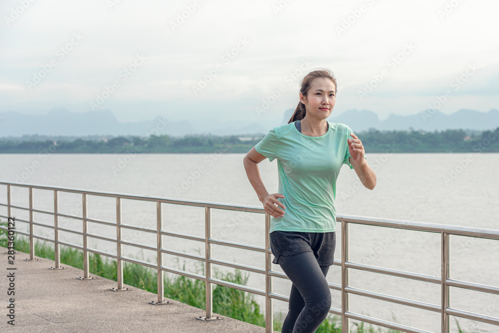 Young fitness Asian woman is running and jogging an outdoor workout on the riverwalk in the morning for lifestyle health. Young fitness Asian woman is running and jogging an outdoor workout on the riverwalk in the morning for lifestyle health.