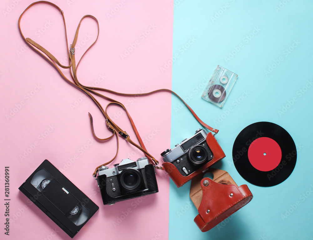 Retro top view still life. Vinyl record, vintage film camera, video and  audio cassette on blue pink pastel background. Flat lay. Top view Stock  Photo