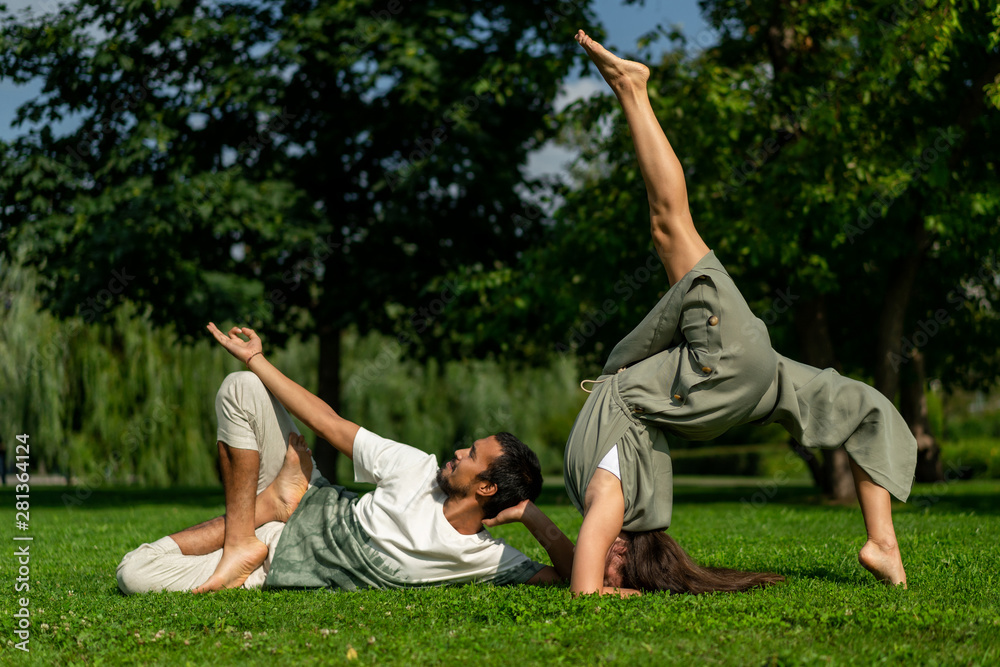 boy and girl different racial affiliation carry out joint practice yoga in city park. summer sunny weather. Tolerance, and respect, calm, peace in world. Different asanas. boy and girl different racial affiliation carry out joint practice yoga in city park. summer sunny weather. Tolerance, and respect, calm, peace in world. Different asanas.
