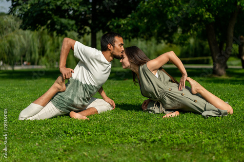 love couple different nationalities conducts joint practice yoga in city park. summer sunny weather. Tolerance, respect, calm. Different asanas shanty yoga.