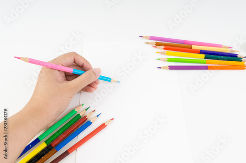 Hand holding two tone pink and blue color pencil to sketching and drawing with the set of colour pencils at the corner of blank drawing paper for kids study and learn art when back school.