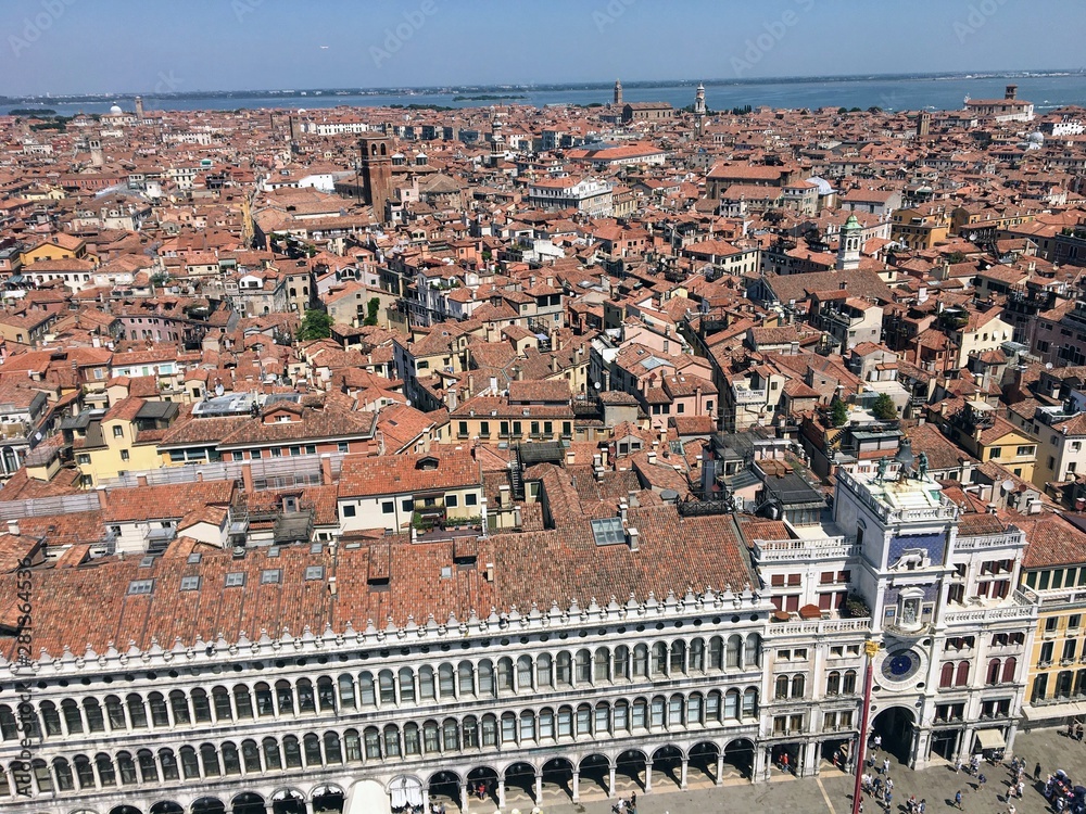 A view from the top of St Marks Campanile of St Marks Square looking down on the square with tourists below and the amazing city of Venice on a beautiful sunny summer day.