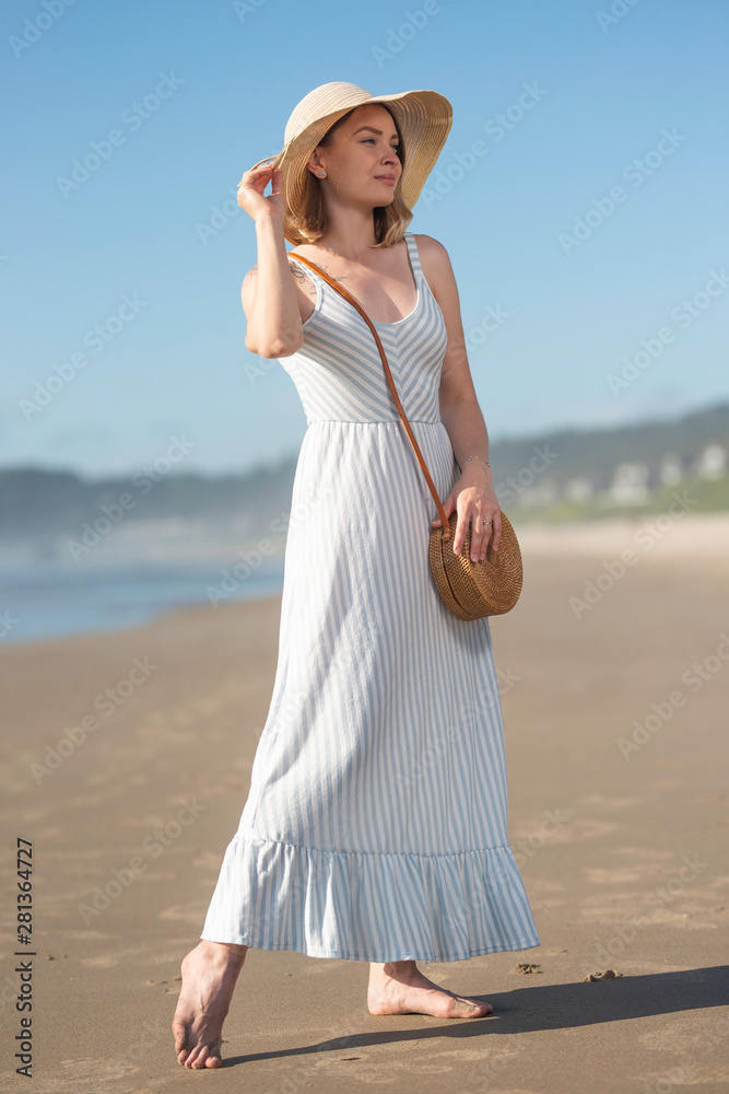 Girl in a hat near the ocean with a rock. Female style and fashion, relaxing on the beach, sunset Girl in a hat near the ocean with a rock. Female style and fashion, relaxing on the beach, sunset