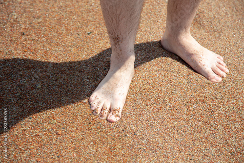 Closeup of bare feet on the beach. Walking on the sand at the water's edge. Vacation and travel concept. Men's feet.