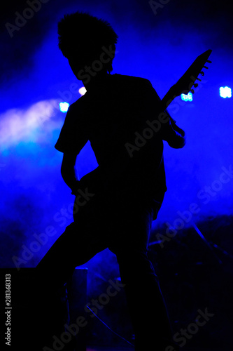 Rock guitarist silhouette with blue background at a concert, India