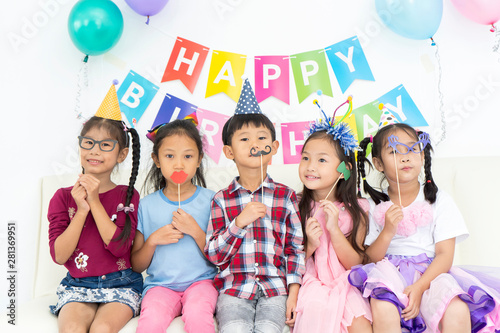 Funny kid with fake mustache and friends. Happy Asian children playing in birthday party. Movember or celebration party, Childhood, holidays, friendship concept