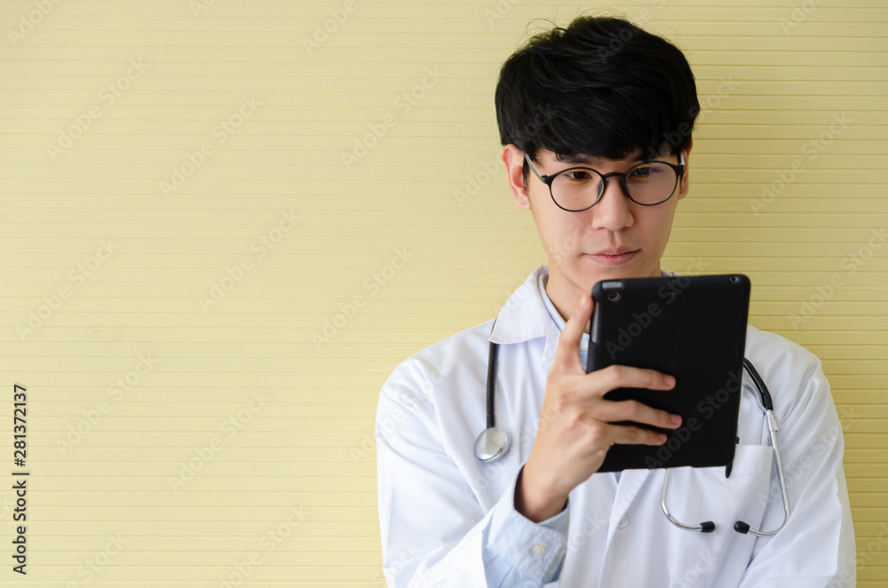 Young doctor in white uniform looking serious at digital tablet Young doctor in white uniform looking serious at digital tablet
