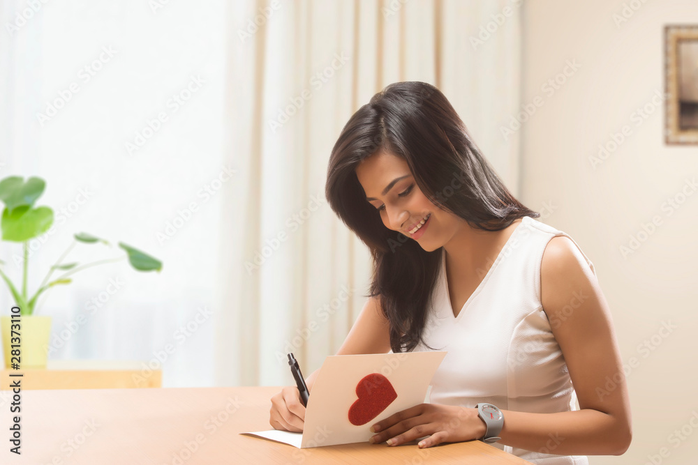 Young woman writing a valentine card at home Young woman writing a valentine card at home
