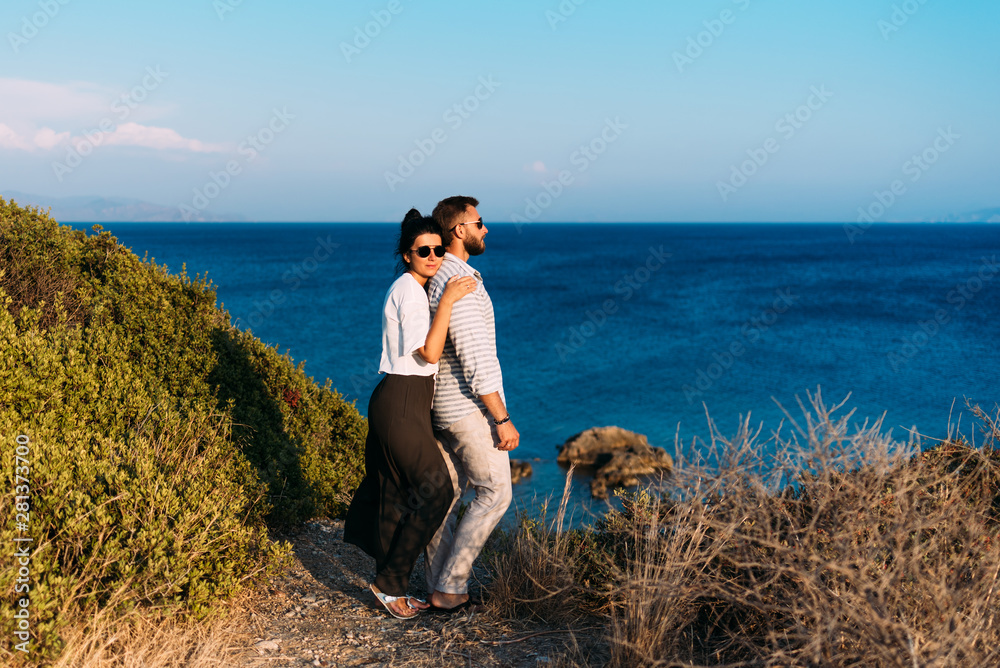 Couple in love at sunset by the sea. Happy couple at sunset.Honeymoon. Honeymoon trip. Man and woman by the sea. Man and woman traveling. Newly married couple. Holiday romance. A lonely pair