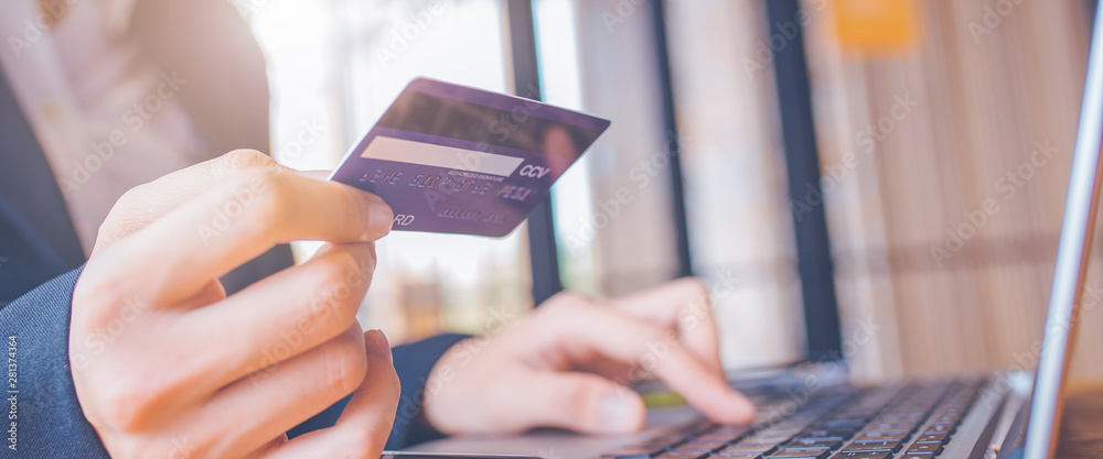 Woman hand holds a blue credit card.And are using a laptop computer.Web banner.
