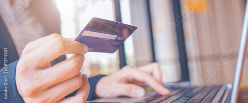 Obraz na płótnie Woman hand holds a blue credit card.And are using a laptop computer.Web banner. w salonie